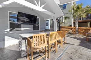Gable roof patio attached to house with open wood frame and outdoor dining setup