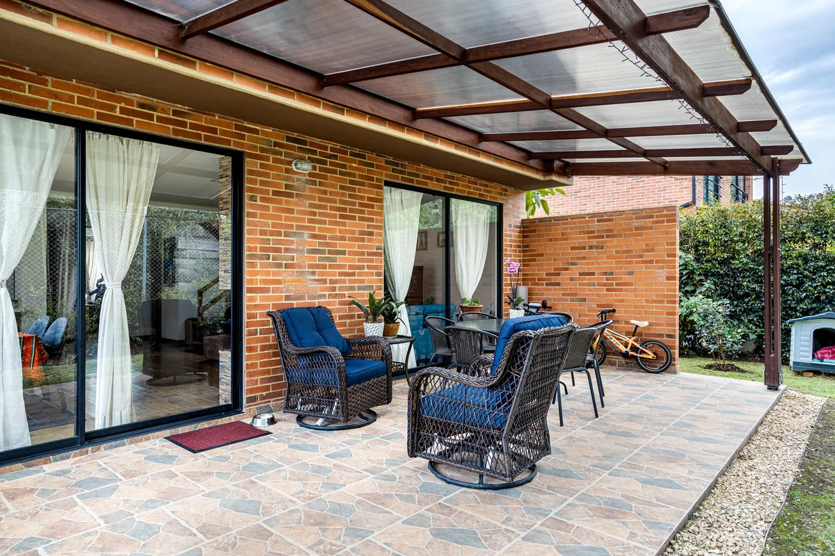 Open-beam wood frame gable roof patio cover attached to brick house