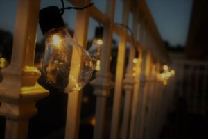 Patio string lights glowing at dusk on a railing