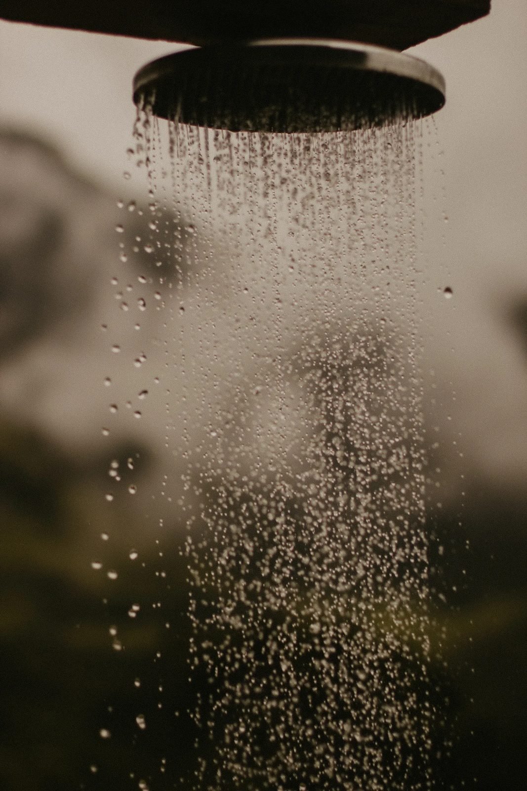 Outdoor shower head spraying water in a garden