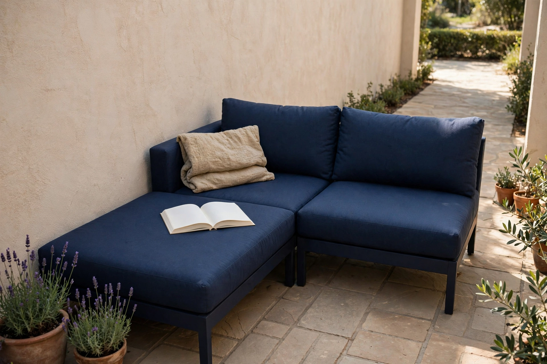 Chaise-ended outdoor sectional for small patio along a wall with book and pillow