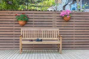 Patio privacy ideas — wooden slat screen with bench and flowers
